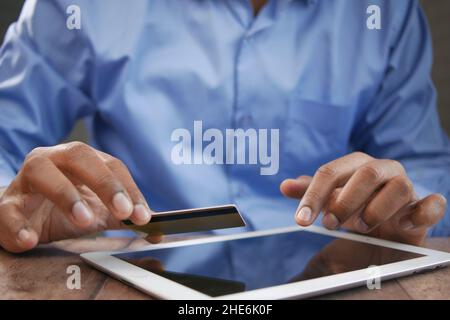 young man putting credit card detail on digital tablet  Stock Photo