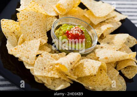 Nachos chips with sauces on black plate Stock Photo