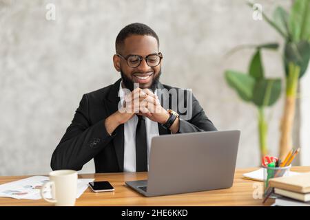 Smiling black man watching video on computer Stock Photo