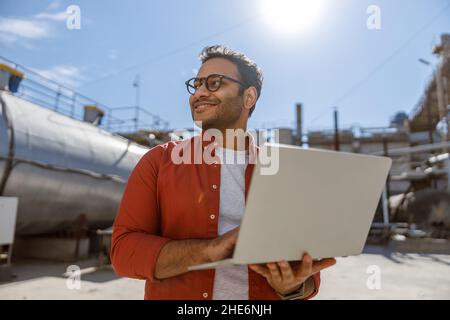 Experienced worker standing in front of large construction plant Stock Photo
