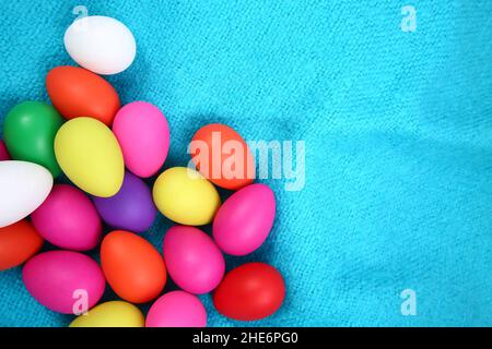 Multi colored painted easter eggs in pink, yellow, red, green, purple and white against a bright blue wool blanket background. Stock Photo