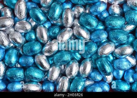 Blue, silver and turquoise foil wrapped chocolate easter eggs, against a black background. Stock Photo