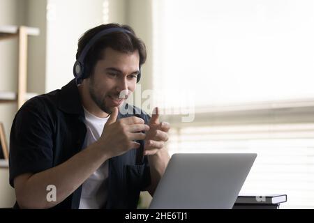 Happy inspired young Caucasian man holding video call conversation. Stock Photo