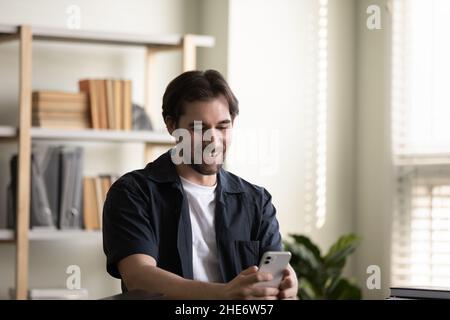 Happy millennial man using cellphone, tech addiction. Stock Photo