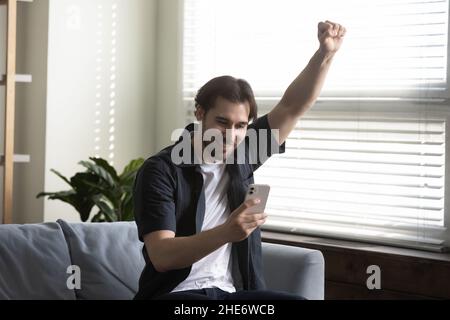 Overjoyed young 30s man celebrating online win. Stock Photo