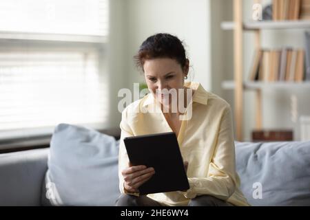 Happy old woman using digital tablet at home. Stock Photo