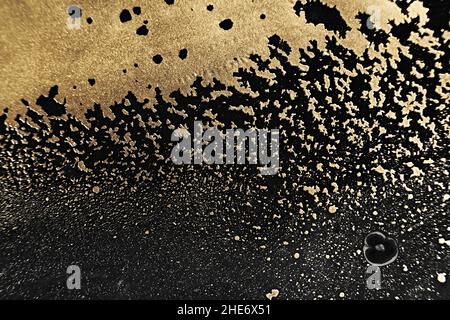 Fluid Art. Metallic gold abstraction and particles on Black background. Marble effect background or texture. Stock Photo