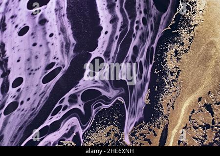 Fluid Art. Metallic gold abstraction and black purple waves. Marble effect background or texture. Stock Photo