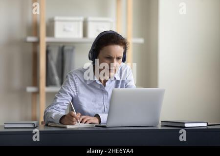 Happy middle aged woman e-learning at home. Stock Photo