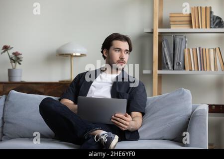 Happy carefree young man using computer at home. Stock Photo