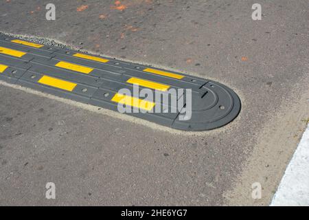 Traffic safety speed bump on an asphalt road. Speed bumps (or speed breakers) are the common name for a family of traffic calming devices. Stock Photo