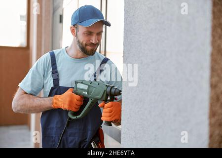 Bearded young man drilling wall with hammer drill Stock Photo