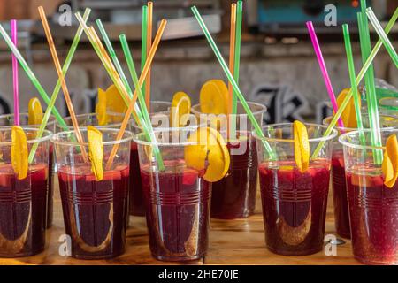 foreground in horizontal view of a row of sangria glasses with orange slices and colored drinking straws.sangria is a refreshing drink native to Spain Stock Photo