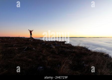 Silhouette of happy woman spreading arms and watching the sunset. Travel Lifestyle success concept adventure active vacations outdoor freedom Stock Photo