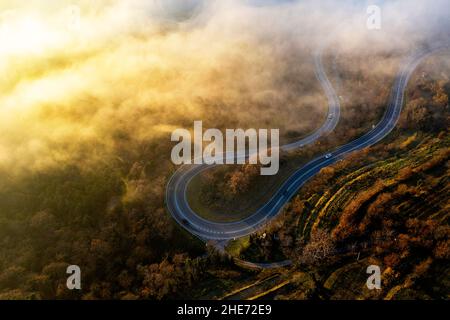 Aerial view of a winding road partly covered with fog at sunset, Kraski rob, Crni Kal village in Slovenia Stock Photo