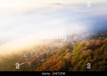Aerial view of Crni Kal village  partly covered with fog at sunset, Kraski rob, Slovenia Stock Photo