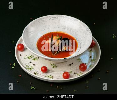 norman fish soup bouillabaisse with seafood in a plate on a black background Stock Photo