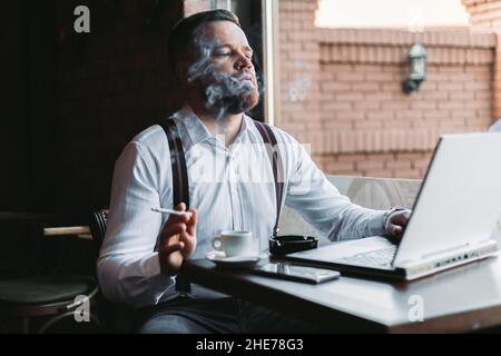 Young businessman working in a cafe, smoking Stock Photo