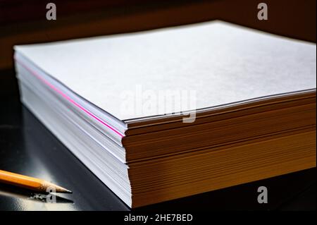 Selective focus on a single colored sheet in a stack of plain white paper Stock Photo