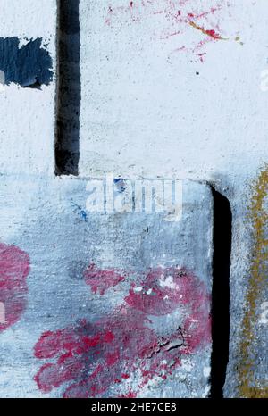 Textured concrete wall with layers of white and gray paint and abstract red handprints. Stock Photo