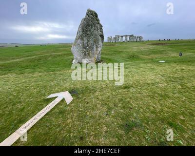 The iconic World Heritage site of Stonehenge.An arrow on the ground points to the direction of Midsummer Sunset Stock Photo