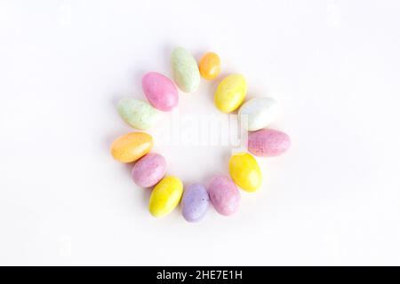 Easter circle made up of sweet colored chocolates. Delicate pastel pink background Stock Photo
