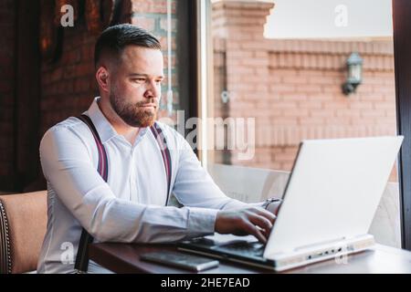 Young businessman working on a laptop in a cafe Stock Photo