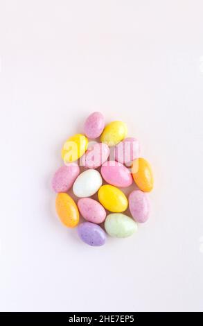 This Easter egg is made up of sweet colored chocolates. Delicate pastel pink background. Stock Photo