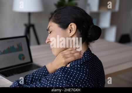 Sad unhappy Indian employee feeling strong neck ache Stock Photo