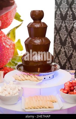 melted chocolate fountain at a celebration to eat with fruit Stock Photo