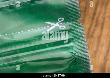 Macro shot of white scissors symbol and dotted cutting line on the plastic food packaging. For cutting along the line, cut above the rest metaphor. Stock Photo