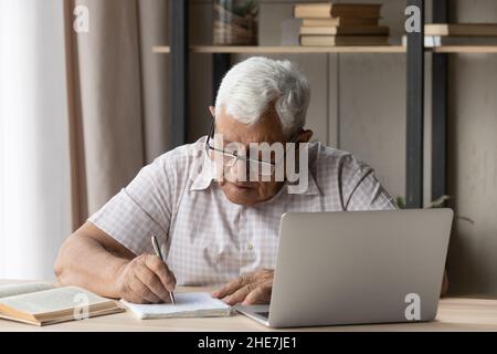Concentrated old man studying on online courses. Stock Photo