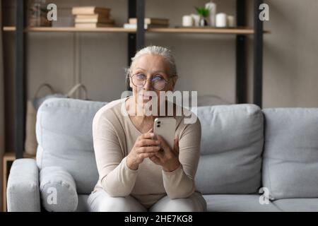 Happy beautiful mature woman using smartphone at home. Stock Photo