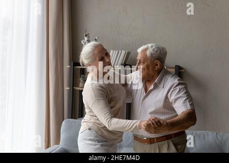 Happy bonding old retired family couple dancing at home. Stock Photo