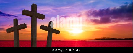 Crucifixion of Jesus Christ. Silhouette of three crosses against sunset sky. Stock Photo
