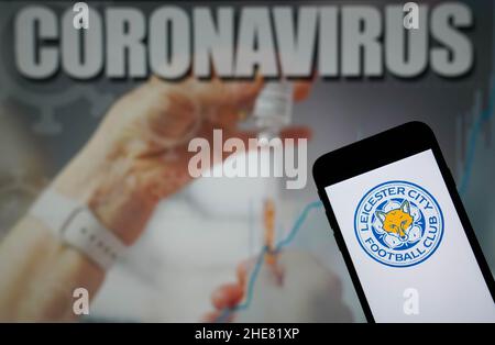 File photo dated 09-01-2021 of the Leicester City Football Club logo seen displayed on a mobile phone with a Coronavirus illustration on a monitor in the background. Leicester's trip to Everton on Tuesday has been postponed after the Foxes successfully applied to the Premier League to have the match rescheduled due to a lack of players. Despite fielding a side strong enough to beat Watford 4-1 in their FA Cup third-round tie on Saturday, Leicester said Covid cases, injuries and the Africa Cup of Nations had left them short. Issue date: Sunday January 9, 2021. Stock Photo