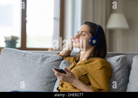 Happy pretty woman in wireless headphones enjoying ambient music Stock Photo