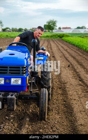 Kherson oblast, Ukraine - May 29, 2021: Senior farmer is working on a tractor. Seasonal worker. Recruiting workers with skills in driving agricultural Stock Photo