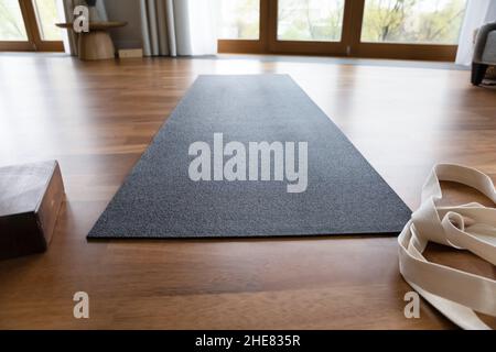 Dark grey yoga mat and strap in empty room Stock Photo