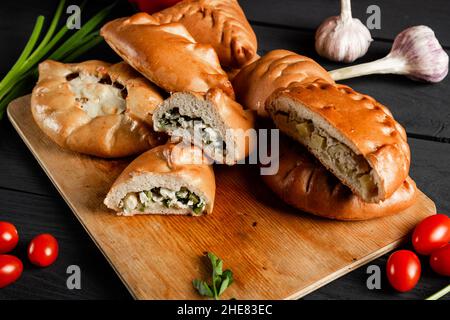 Pies on a cutting board. Composition on a black background with ingredients. Stock Photo