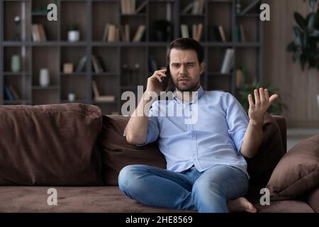 Angry dissatisfied man talking on phone, arguing or solving problem Stock Photo
