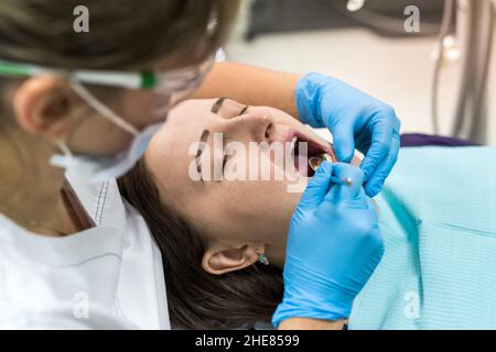 Dentist checking patient's teeth with mirror in dentistry Stock Photo