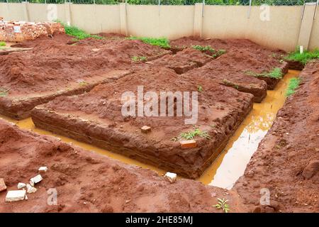 Building foundation that was dug in sand soil. The dug out soil was placed in mounts around the trenches. Water in the trenches Stock Photo