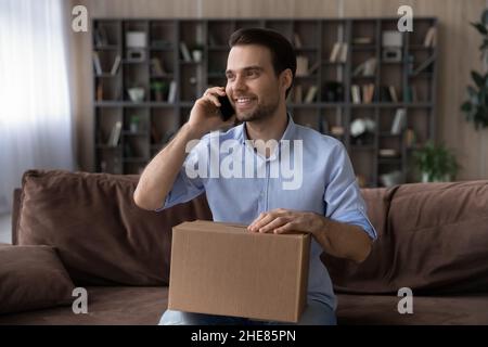 Smiling man making phone call to customer service, received parcel Stock Photo