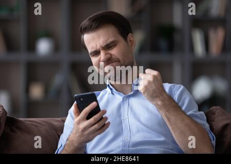 Head shot of unhappy angry man having problem with smartphone Stock Photo