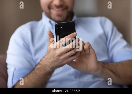 Cropped close up smiling man using smartphone in hands Stock Photo