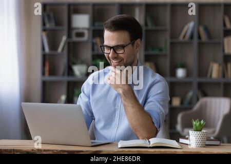 Excited businessman in glasses looking at laptop screen, reading good news Stock Photo