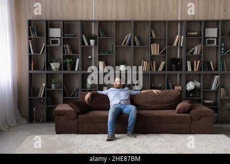 Full length relaxed man sitting on comfortable couch at home Stock Photo