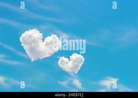 Two heart shaped clouds high in the bright blue sky. Pair of white cloud hearts in the azure heaven. Valentine day design element. Love concept. Stock Photo