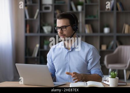 Focused businessman in glasses and headset making video call Stock Photo